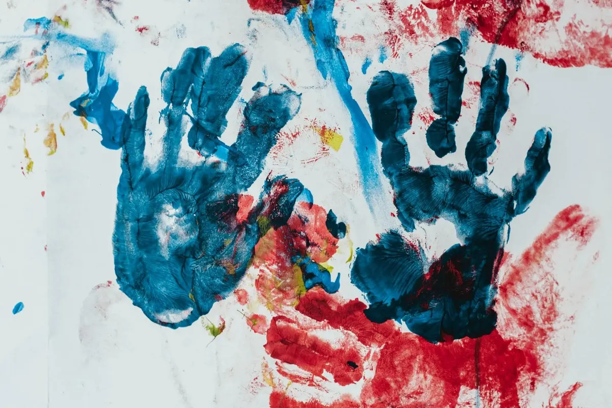 Blaue und rote Handabdrücke in Fingerfarbe auf weißem Papier